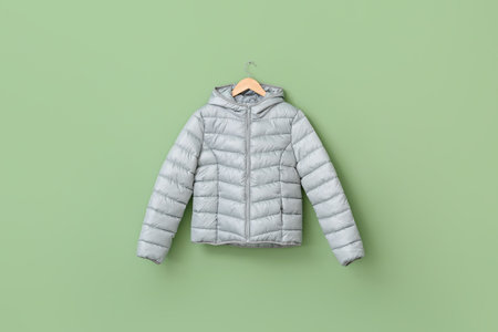 Hanger with stylish puffer jacket on color backgroundの写真素材