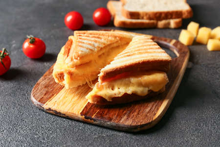 Board with tasty sandwiches on dark background, closeup