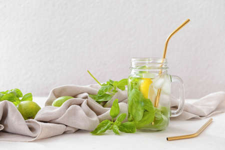 Mason jar of lemonade with basil on light background