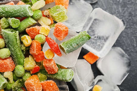 Mix of frozen vegetables and ice cubes on dark background, closeupの写真素材