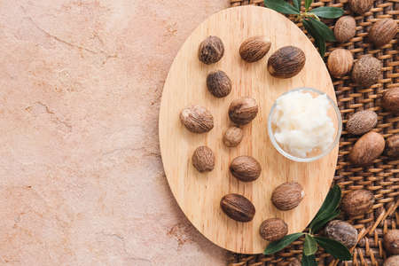 Wooden board with shea butter and nuts on color background, closeupの写真素材