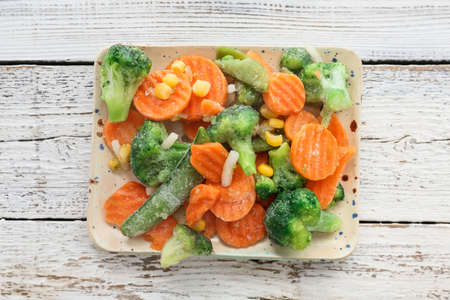 Plate with different frozen vegetables on light wooden backgroundの写真素材