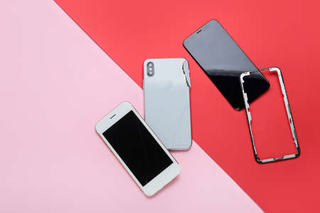 Damaged mobile phones, display glass on pink and red background