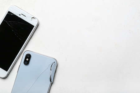 Broken mobile phones on white background, closeup