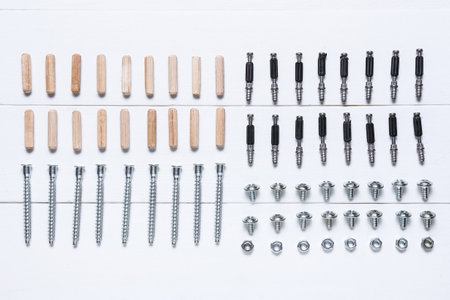 Set of bolts, nuts and dowels on white wooden backgroundの写真素材