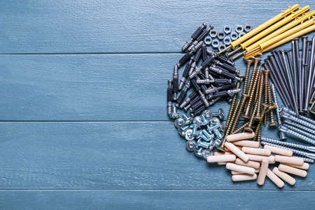 Different nuts, bolts, screws, dowels, nails and furniture corners on color wooden background