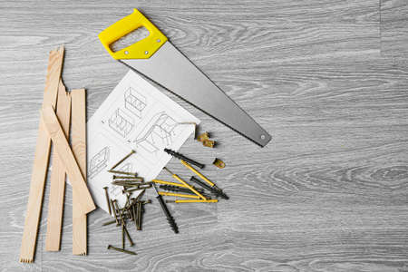 Furniture assembling instructions, planks, saw, furniture corners, different screws and dowels on...