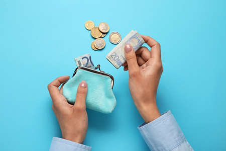 Woman putting money into wallet on blue backgroundの写真素材