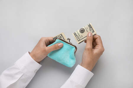 Woman taking money from wallet on gray backgroundの写真素材