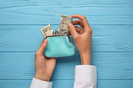 Woman taking money from wallet on blue wooden backgroundの写真素材