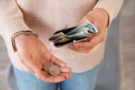 Woman holding wallet with coins, closeup
