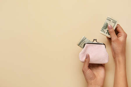 Woman with pink wallet and banknotes on beige backgroundの写真素材