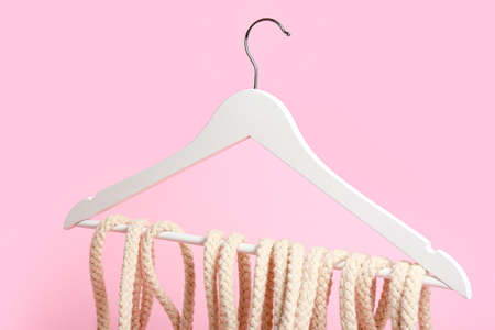 Clothes hanger with rope on color background