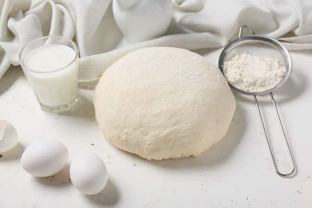 Raw dough with ingredients on light background
