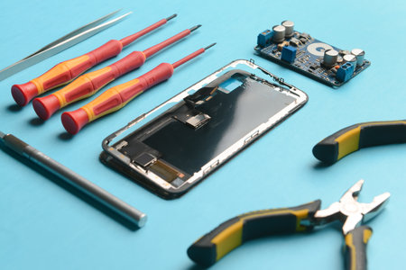 Disassembled mobile phone with technician tools on color backgroundの写真素材