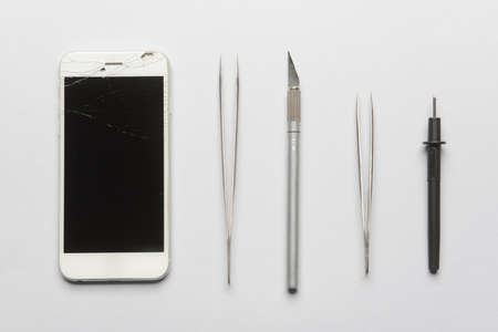 Damaged mobile phone with technician tools on gray backgroundの写真素材
