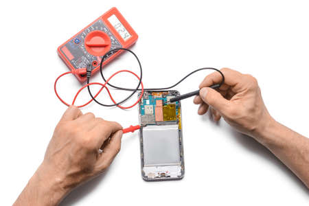 Male technician repairing damaged mobile phone on white background