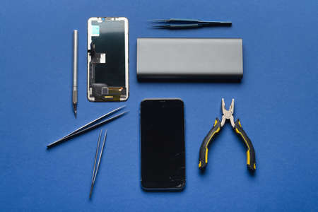 Disassembled mobile phone with technician tools on color background