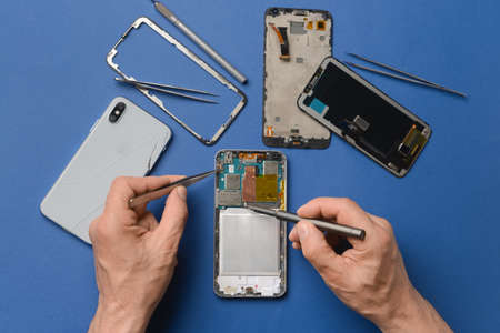 Male technician repairing damaged mobile phone on color backgroundの写真素材
