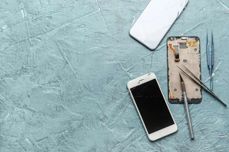 Damaged mobile phones with technician tools on color backgroundの写真素材