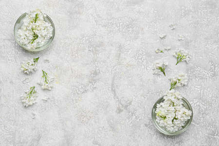Bowls with beautiful lilac flowers on light background