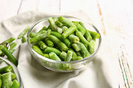 Bowl with frozen green beans on light wooden backgroundの写真素材