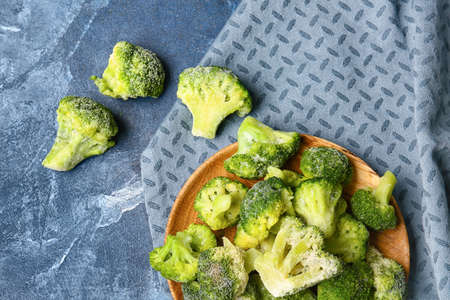 Plate with frozen broccoli on color background