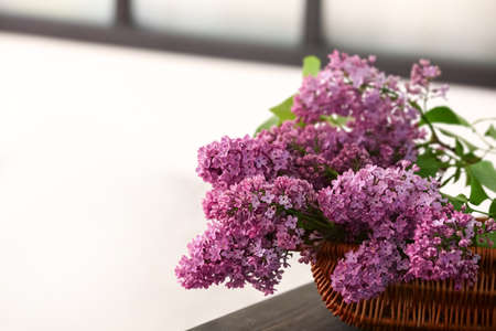 Basket with lilac flowers on table, closeup