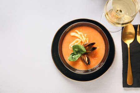 Bowl with tasty Cacciucco soup and glass of wine on table