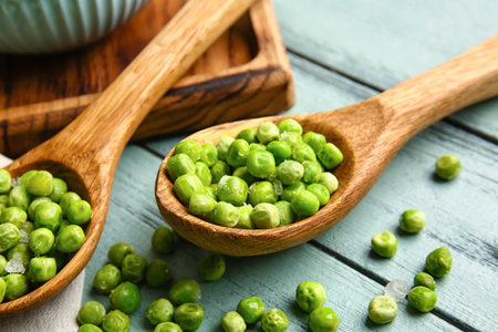 Spoons with frozen green peas on wooden backgroundの写真素材