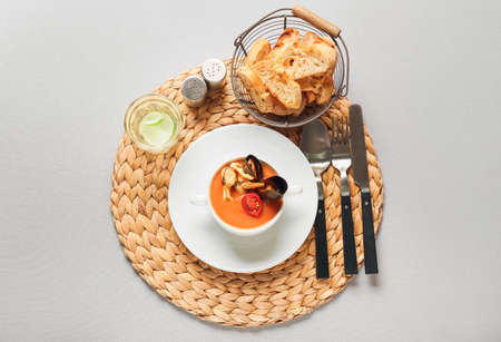 Pot with tasty Cacciucco soup, glass of water and bread on tableの写真素材