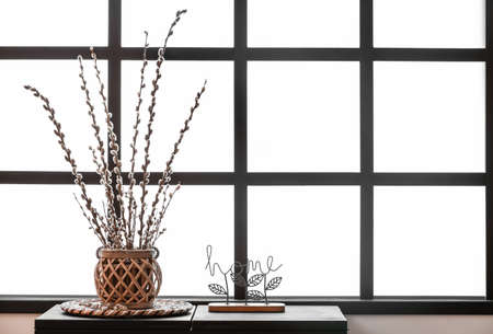 Vase with willow branches and decor on table near windowの写真素材