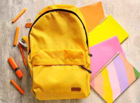 School backpack with stationery on light background