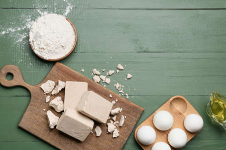 Board with fresh yeast, flour and eggs on color wooden background