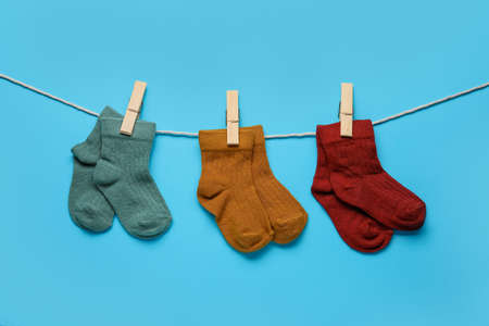 Different baby socks hanging on rope against color backgroundの写真素材
