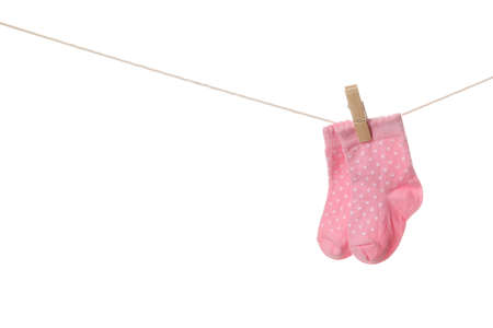 Baby socks hanging on rope against white backgroundの写真素材