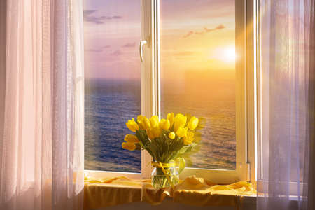 Vase with yellow tulip flowers near window with beautiful view