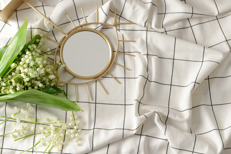Beautiful lily-of-the-valley flowers and mirror on light fabricの写真素材