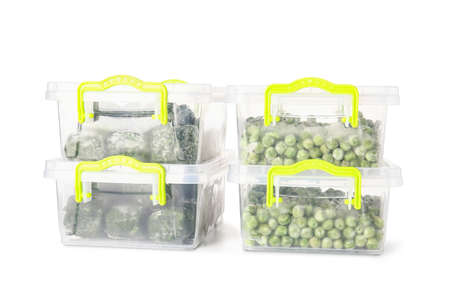 Plastic containers with frozen spinach and green peas on white background
