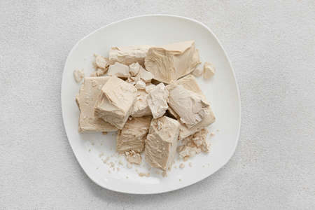 Plate with fresh yeast on light background