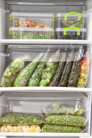 Containers and plastic bags with vegetables in refrigeratorの写真素材
