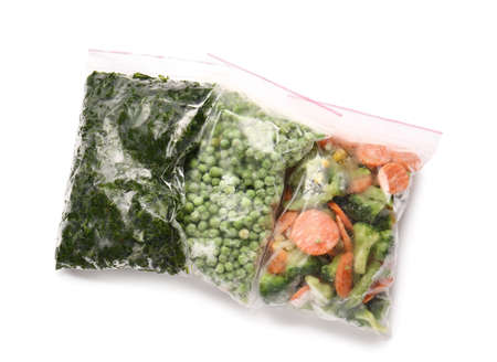 Plastic bags with frozen vegetables on white background