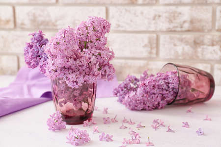 Glasses with beautiful lilac flowers on light backgroundの写真素材