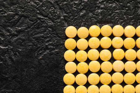 yellow pills on dark backgroundの写真素材