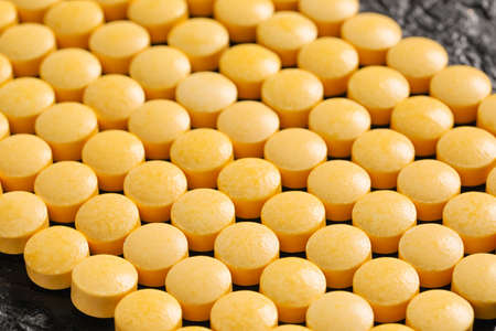 Yellow pills on dark background, closeup
