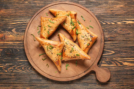 Board with tasty Uzbek samsa on wooden backgroundの写真素材