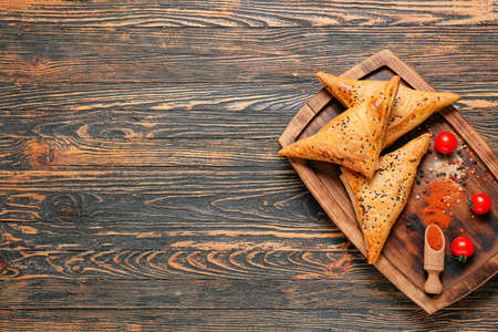 Board with tasty Uzbek samsa on wooden backgroundの写真素材
