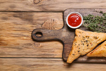 Board with tasty Uzbek samsa and tomato sauce on wooden backgroundの写真素材