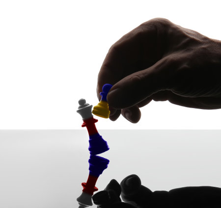 Silhouette of male hand with chess pieces in colors of Ukrainian and Russian flags against white background. Russia vs Ukraine warの写真素材