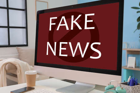 Text FAKE NEWS on screen of computer monitor on tableの写真素材